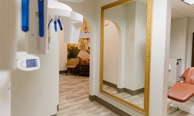 A bright, white hallway with arched doorways and a large gold-framed mirror on the wall.