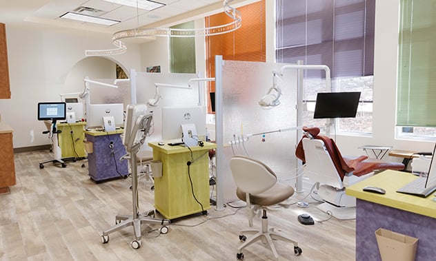 A close-up view of a dental treatment area with a white chair and digital monitors.