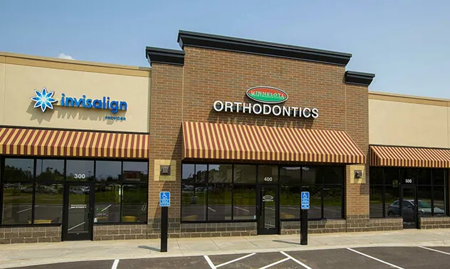 The exterior storefront of a dental office located in a modern commercial building with large glass windows.