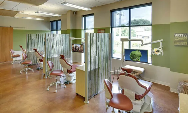 A bright, spacious orthodontic clinic area with multiple treatment chairs separated by glass partitions.