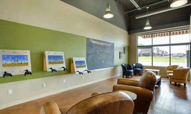 A comfortable seating area with leather chairs facing a counter with computer monitors, likely for parents or consultations.
