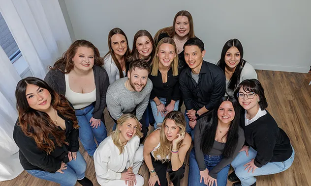 A group portrait of the dental office staff standing together, with one member sitting in the center holding a giant red toothbrush.