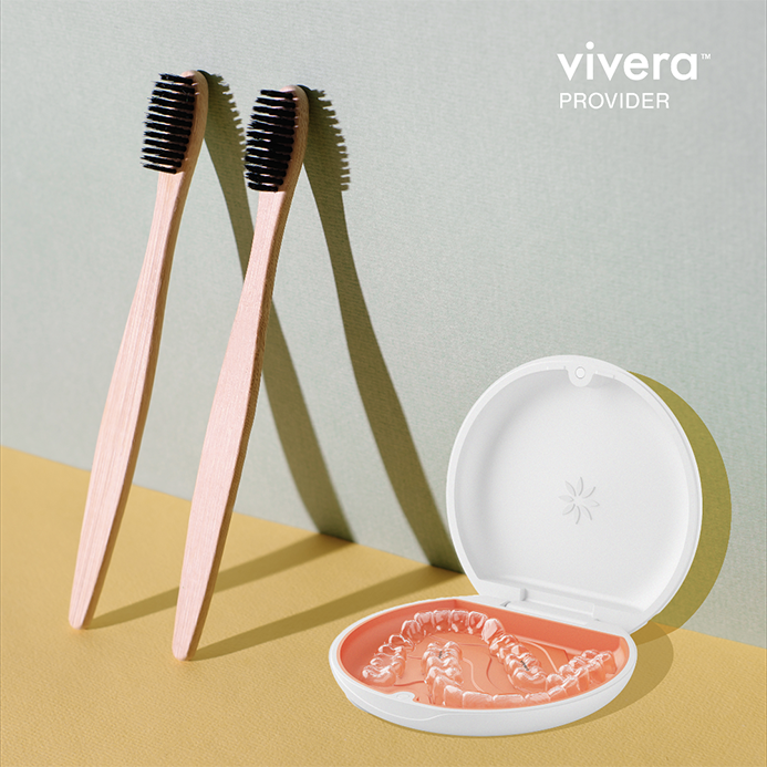 A display of clear Vivera retainers alongside two circular storage cases and dental cleaning tools.