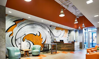 A reception area featuring a large, stylized orange and white mural behind the front desk.