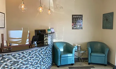 A view of a stylish reception desk with a mosaic tile front and two teal leather armchairs.