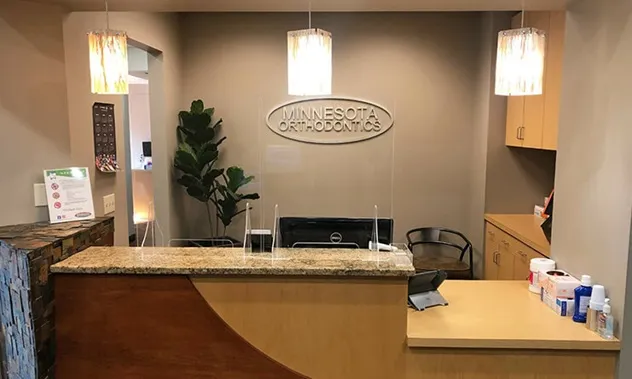 A warm, inviting reception area with a curved wooden desk and soft hanging pendant lights.
