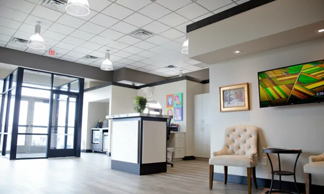 A clean, minimalist reception area with a white front desk and comfortable seating for patients.