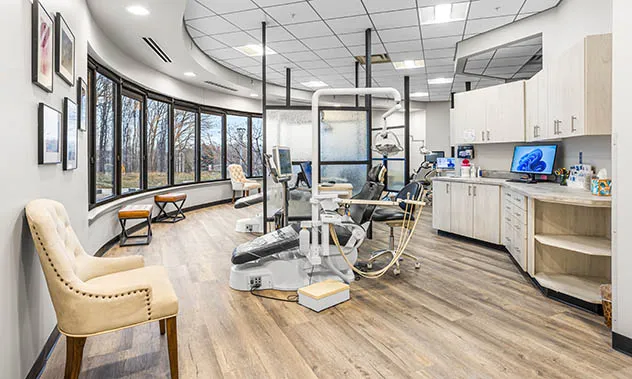 A bright, circular treatment area with multiple dental chairs, large windows, and modern wooden flooring.