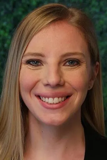 A headshot of Ashley G. – Treatment Coordinator with long blonde hair against a green textured background.